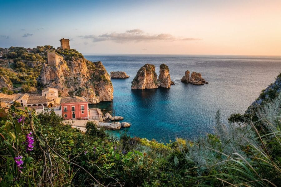 Βραχονησίδες και πέτρινα κτίσματα σε κόλπο της Σικελίας στο ηλιοβασίλεμα